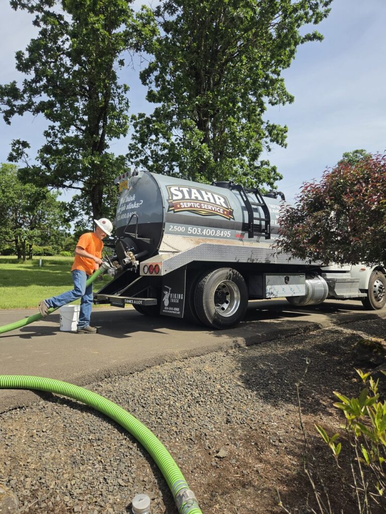 Stahr Septic Service pump truck with green hose connected to a residential septic tank during a pump-out in Salem, Oregon — fast, thorough, and owner-operated on every call.